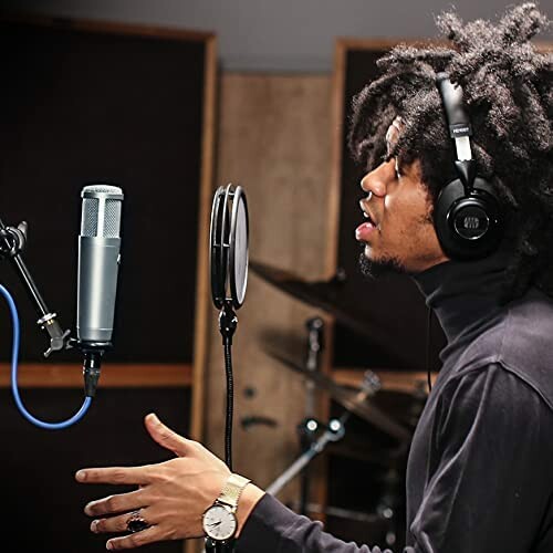 Person singing into a microphone in a recording studio